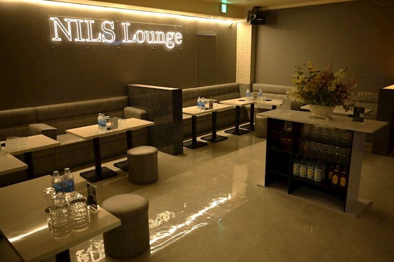 NILS Lounge の店内。壁の店名サインとソファのテーブル席