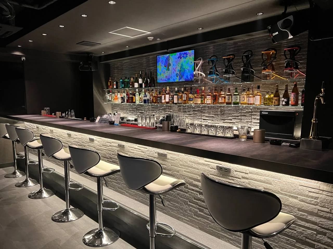 Bar Link 草加店のカウンター席。白い椅子が並び、奥に酒棚とシーシャ